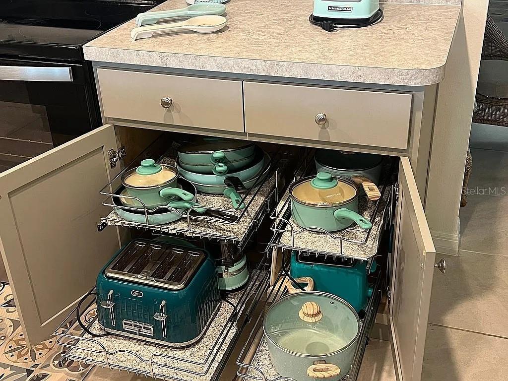 A kitchen cabinet with pull-out shelves containing cookware and small appliances — 2711 NEVERLAND DRIVE, NEW SMYRNA BEACH, FL
