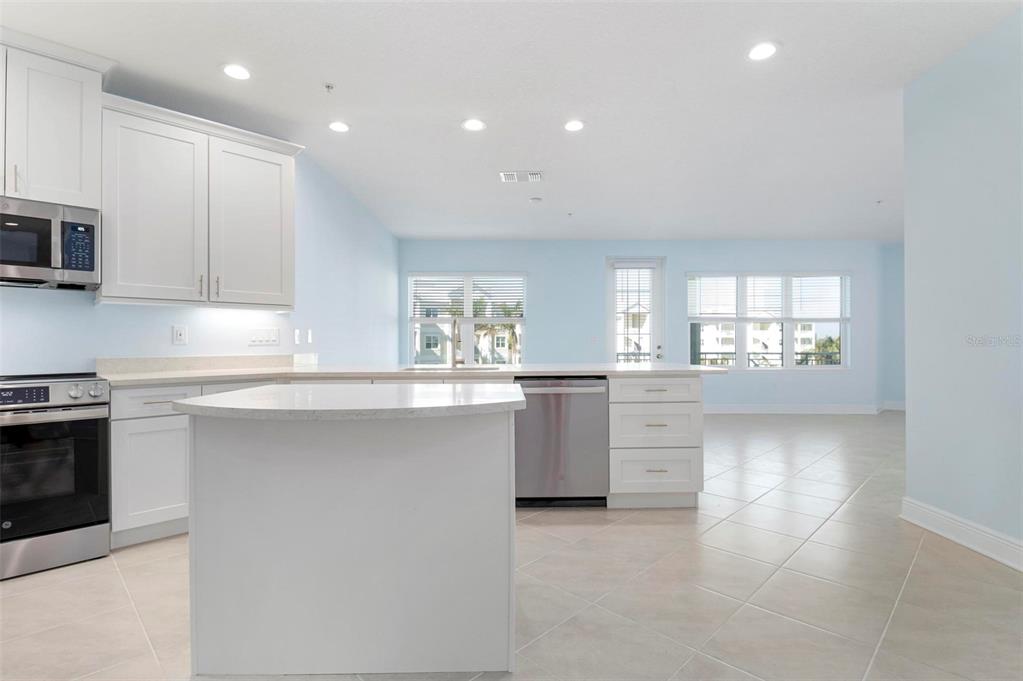 A kitchen with white cabinets, stainless steel appliances, a center island, and light-colored tile flooring — 3426 79TH STREET CIRCLE W UNIT 202, BRADENTON, FL