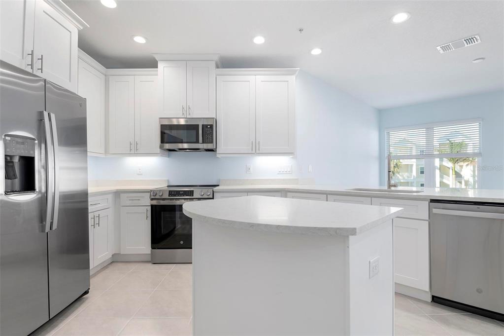 A modern kitchen features white cabinets, stainless steel appliances, and a central island — 3426 79TH STREET CIRCLE W UNIT 202, BRADENTON, FL