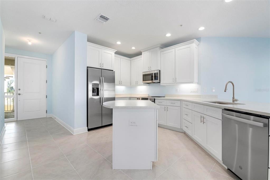 A kitchen features white cabinets, stainless steel appliances, a center island, and light tile flooring — 3426 79TH STREET CIRCLE W UNIT 202, BRADENTON, FL