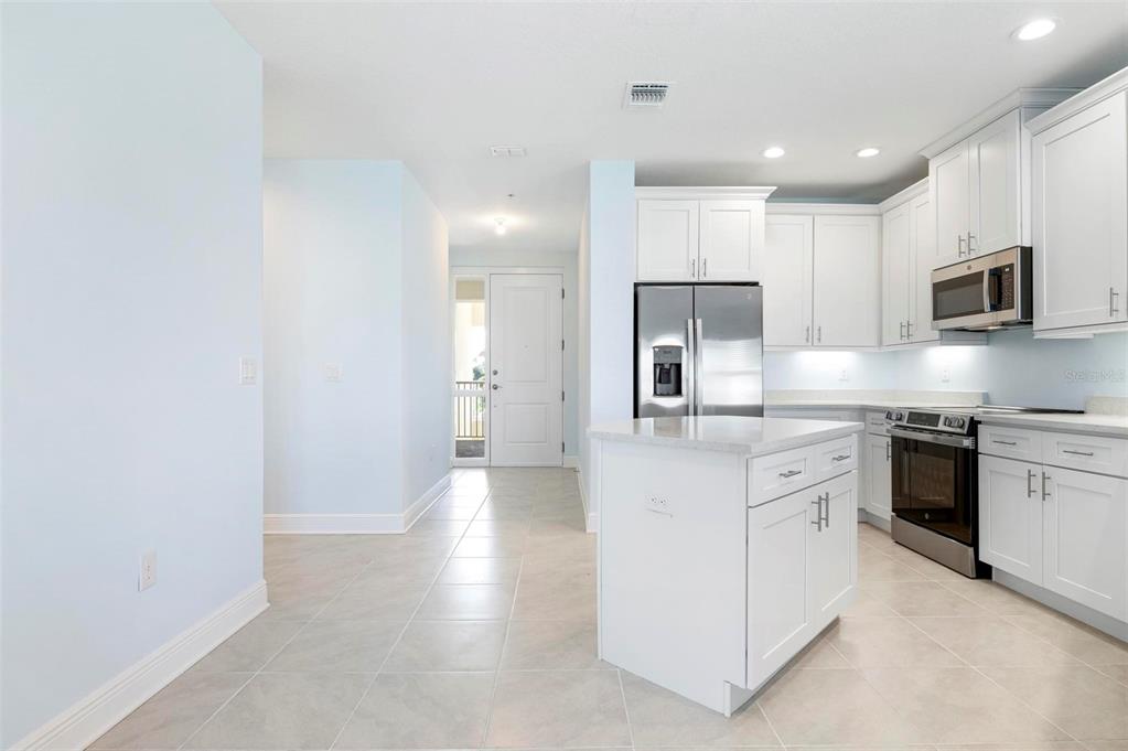A kitchen with white cabinets, stainless steel appliances, and a central island on tile flooring — 3426 79TH STREET CIRCLE W UNIT 202, BRADENTON, FL