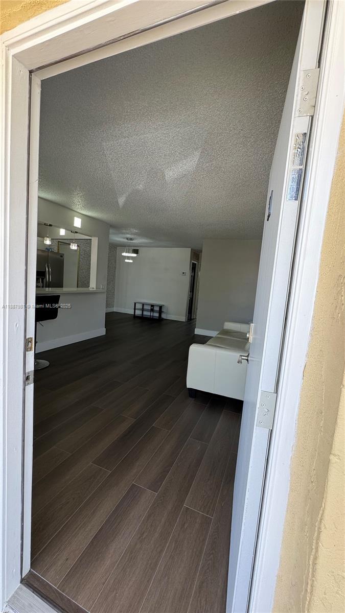 A view through an open doorway into a living area with dark wood-look flooring — 160 NE 203rd Ter # E31, Miami Gardens FL 33179, MIAMI GARDENS, FL