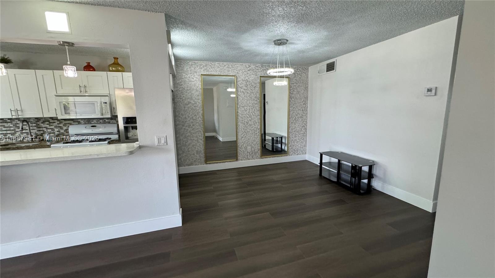 A dining area features wood-look flooring, two wall mirrors, and a modern chandelier — 160 NE 203rd Ter # E31, Miami Gardens FL 33179, MIAMI GARDENS, FL
