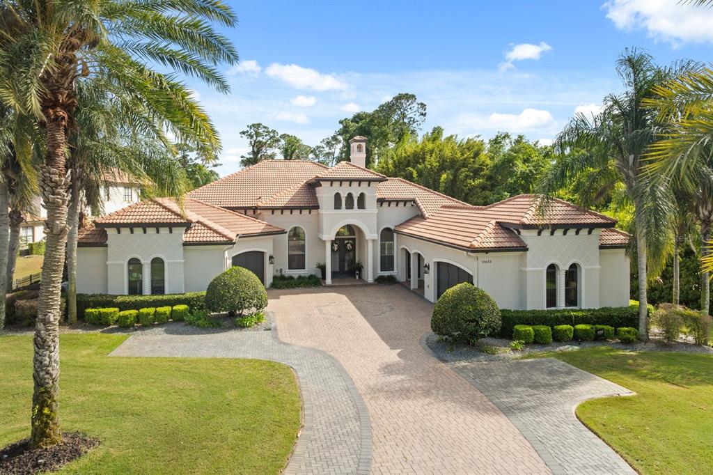 A large, single-story Mediterranean-style house with a tile roof and a paved circular driveway — 10633 LAGO BELLA DRIVE, ORLANDO, FL