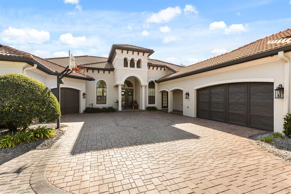 A paved driveway leads to the entrance and garages of a Mediterranean-style home — 10633 LAGO BELLA DRIVE, ORLANDO, FL