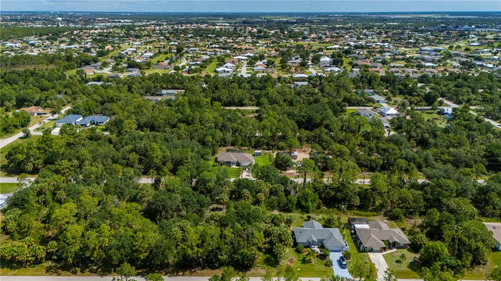 An aerial view shows a residential neighborhood with houses surrounded by dense trees and vegetation — 11440 3RD AVENUE, PUNTA GORDA, FL