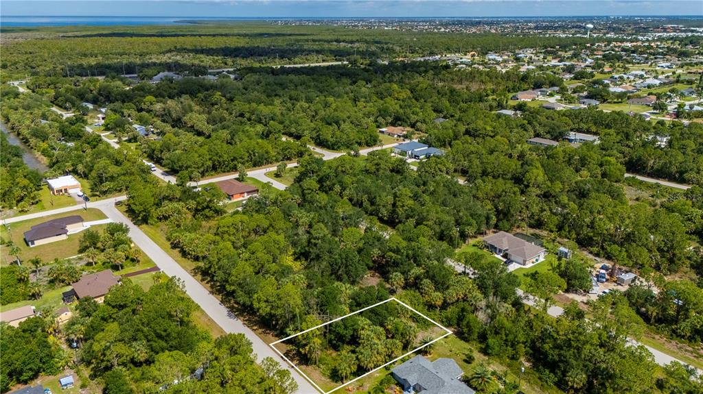 An aerial view shows a rectangular vacant lot surrounded by trees and residential houses — 11440 3RD AVENUE, PUNTA GORDA, FL