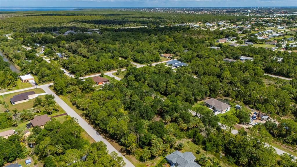 An aerial view shows a suburban neighborhood with scattered houses surrounded by dense green trees — 11440 3RD AVENUE, PUNTA GORDA, FL