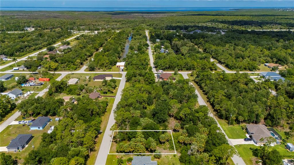 An aerial view shows a rectangular vacant lot surrounded by trees and residential houses — 11440 3RD AVENUE, PUNTA GORDA, FL