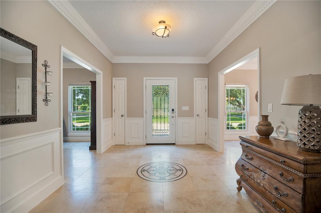 A foyer with tile flooring, wainscoting, a central medallion, and a glass-paneled front door — 8368 RAMBLING RIVER DRIVE, SANFORD, FL