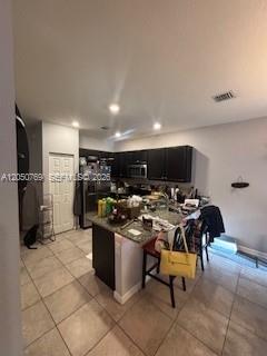 A kitchen features dark cabinetry, a granite-topped island with bar stools, and tile flooring — 162 SE 33rd Ter, Homestead FL 33033, HOMESTEAD, FL
