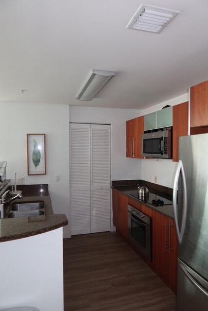 A kitchen features wood cabinets, granite countertops, stainless steel appliances, and a white louvered closet — 300 S Biscayne Boulevard # T1902, Miami FL 33131, MIAMI, FL