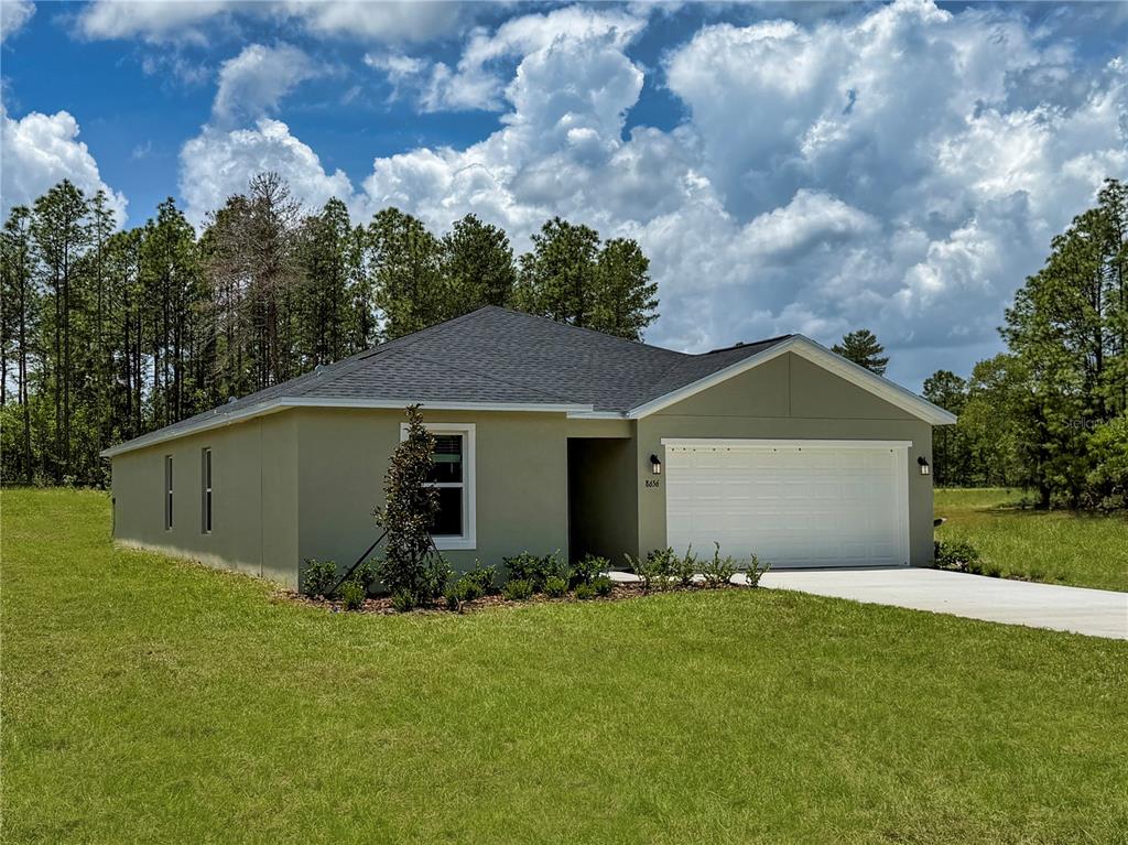 A single-story house with a green stucco exterior, a two-car garage, and a dark roof — 8445 SW 41ST CIRCLE, OCALA, FL