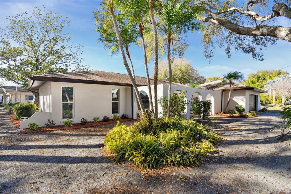 A single-story house with a white exterior, arched entryway, and palm trees in the front yard — 570 CASLER AVENUE, CLEARWATER, FL