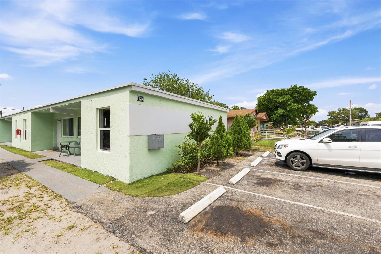 A light green single-story building with a parking lot and a white car — 166 SW 3rd Street # d, Deerfield Beach FL 33441, DEERFIELD BEACH, FL
