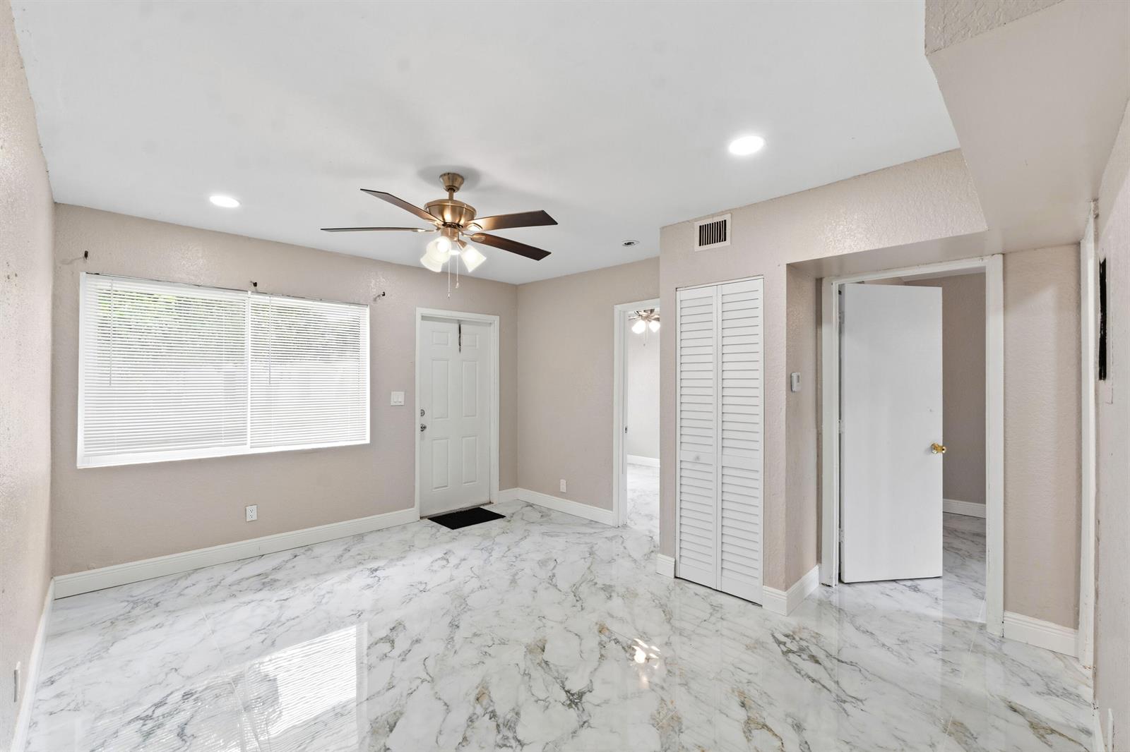 A room with white marble-patterned tile flooring, a ceiling fan, and multiple white doors — 166 SW 3rd Street # d, Deerfield Beach FL 33441, DEERFIELD BEACH, FL