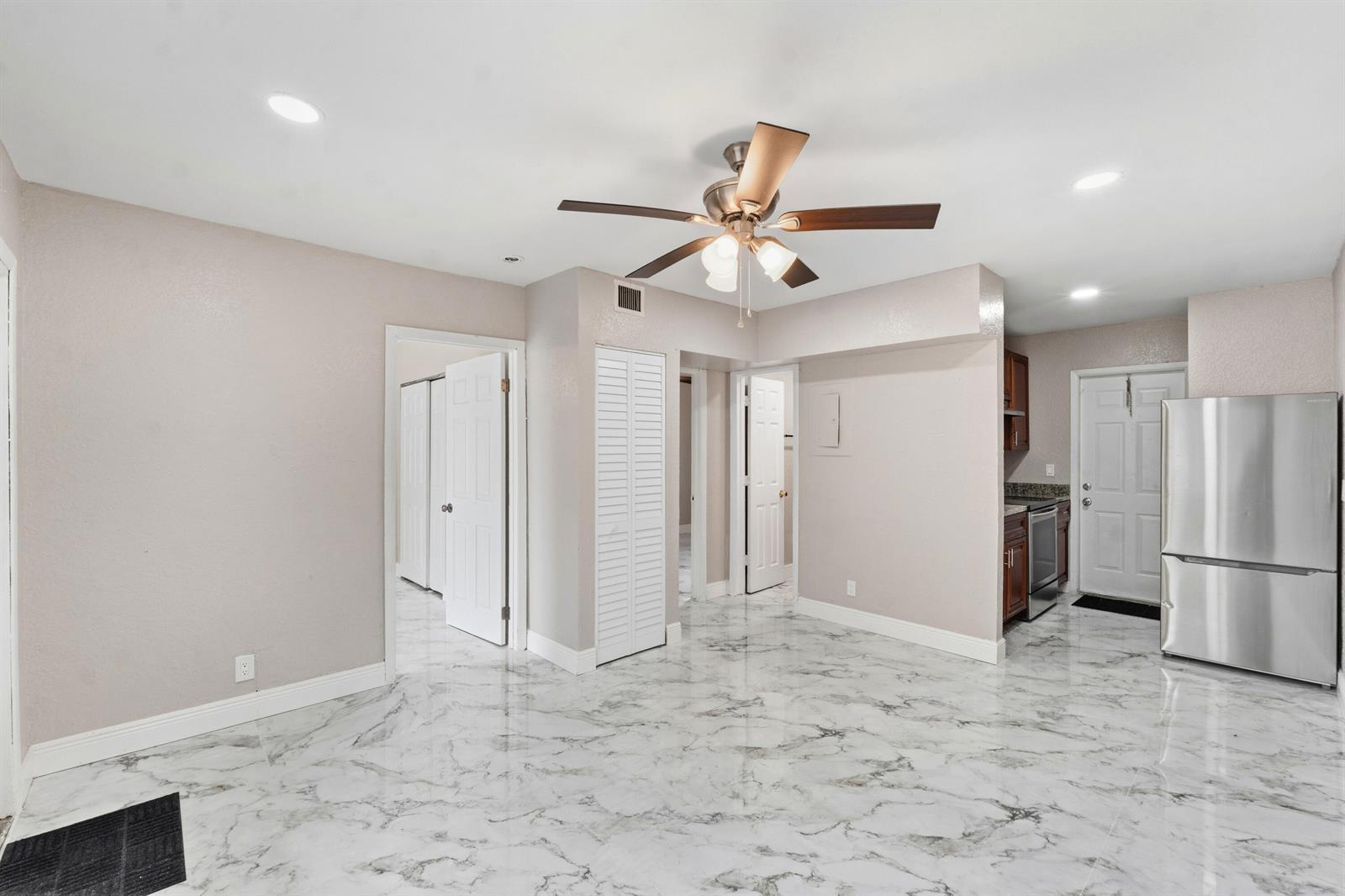 An open-concept room features white marble-patterned tile flooring, a ceiling fan, and a stainless refrigerator — 166 SW 3rd Street # d, Deerfield Beach FL 33441, DEERFIELD BEACH, FL
