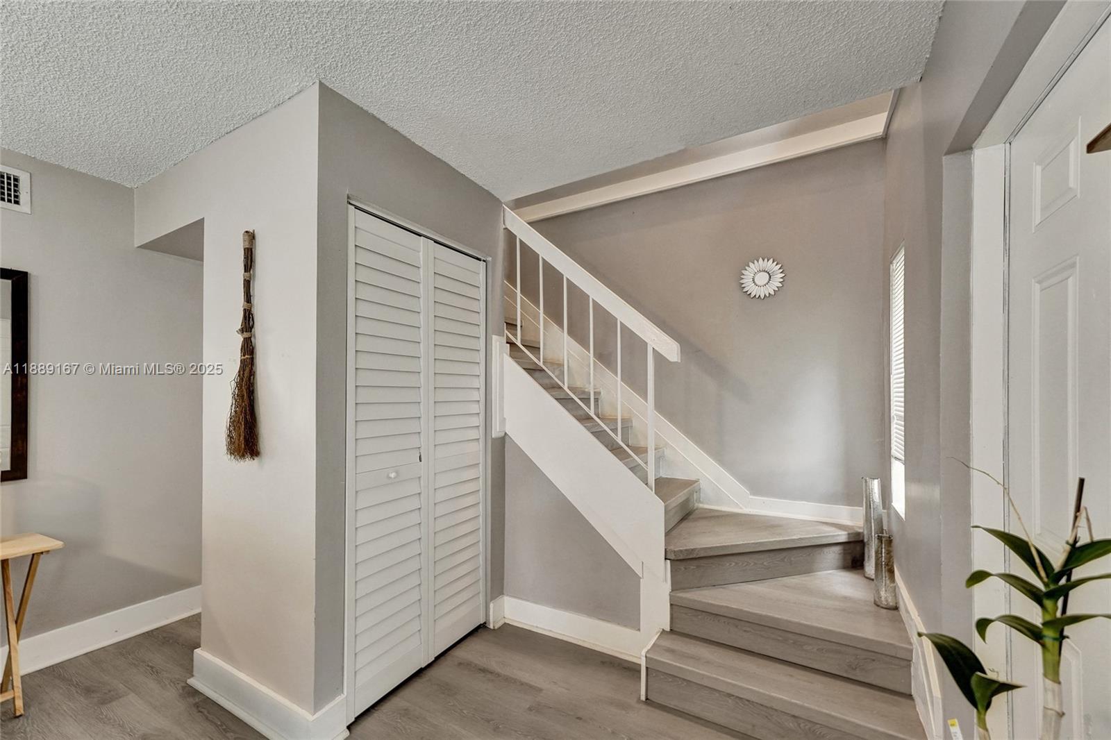 An entryway features gray flooring, a white staircase with a railing, and a louvered closet — 2218 NW 59th Way # B, Lauderhill FL 33313, LAUDERHILL, FL
