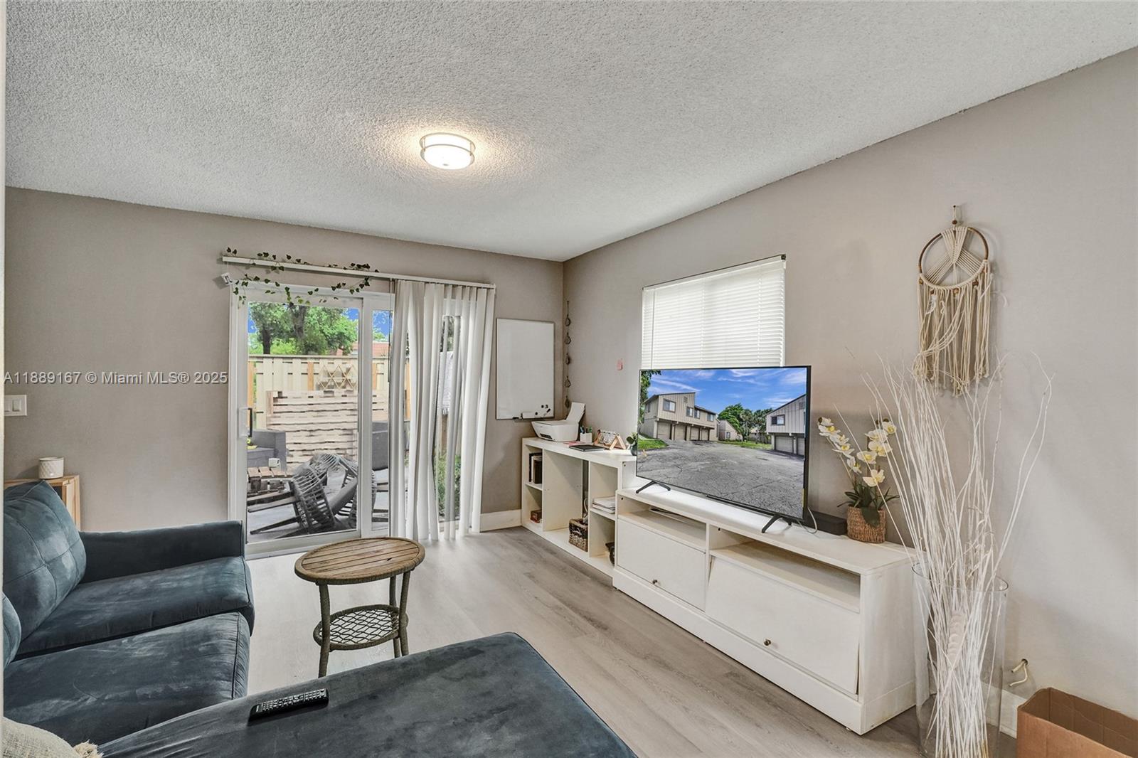 A living room features a blue sectional sofa, a white media console, and sliding glass doors — 2218 NW 59th Way # B, Lauderhill FL 33313, LAUDERHILL, FL