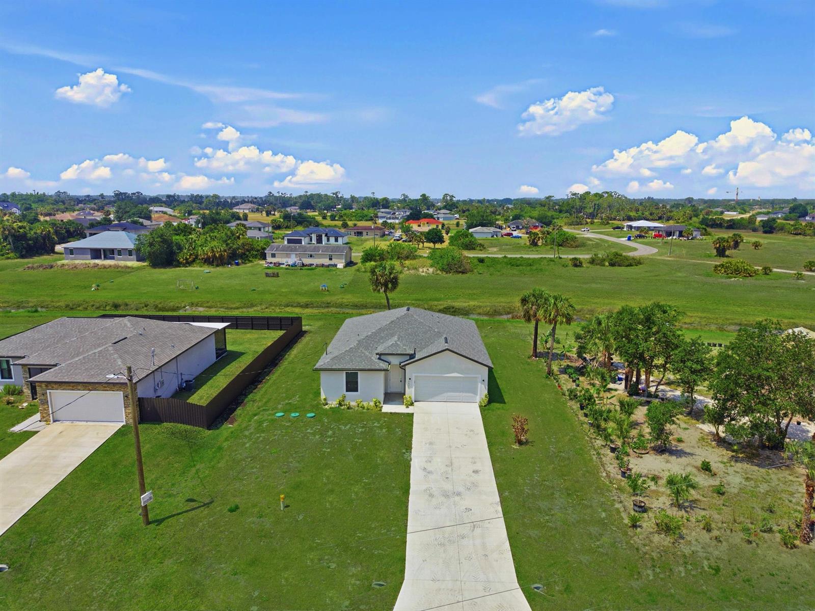 An aerial view shows a single-story house with a concrete driveway and a large yard — 3031 NE Beechwood Circle, FL 33935, FL