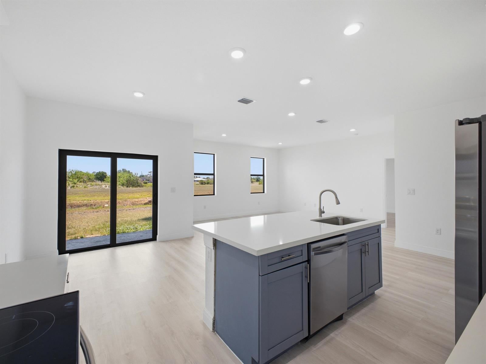 A kitchen island with blue cabinets and a stainless steel dishwasher faces a living area — 3031 NE Beechwood Circle, FL 33935, FL