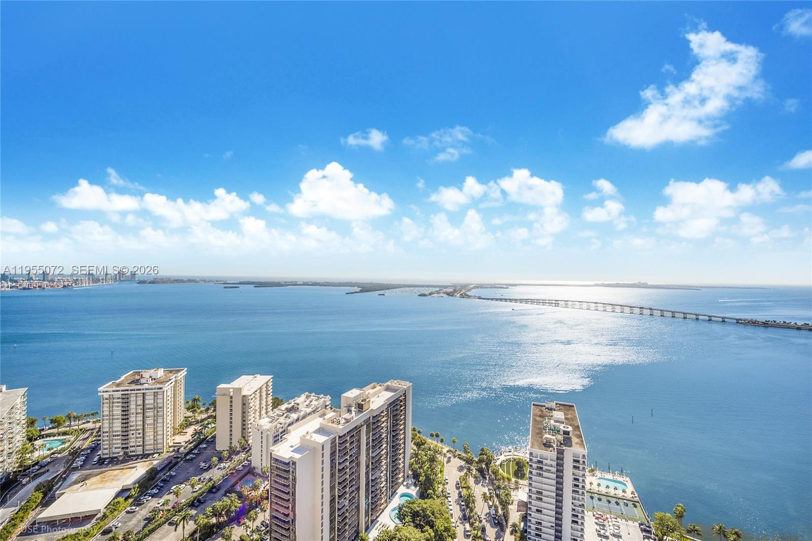 An aerial view shows high-rise apartment buildings overlooking a large bay and a long bridge — 1451 Brickell Ave # 3902, Miami FL 33131, MIAMI, FL