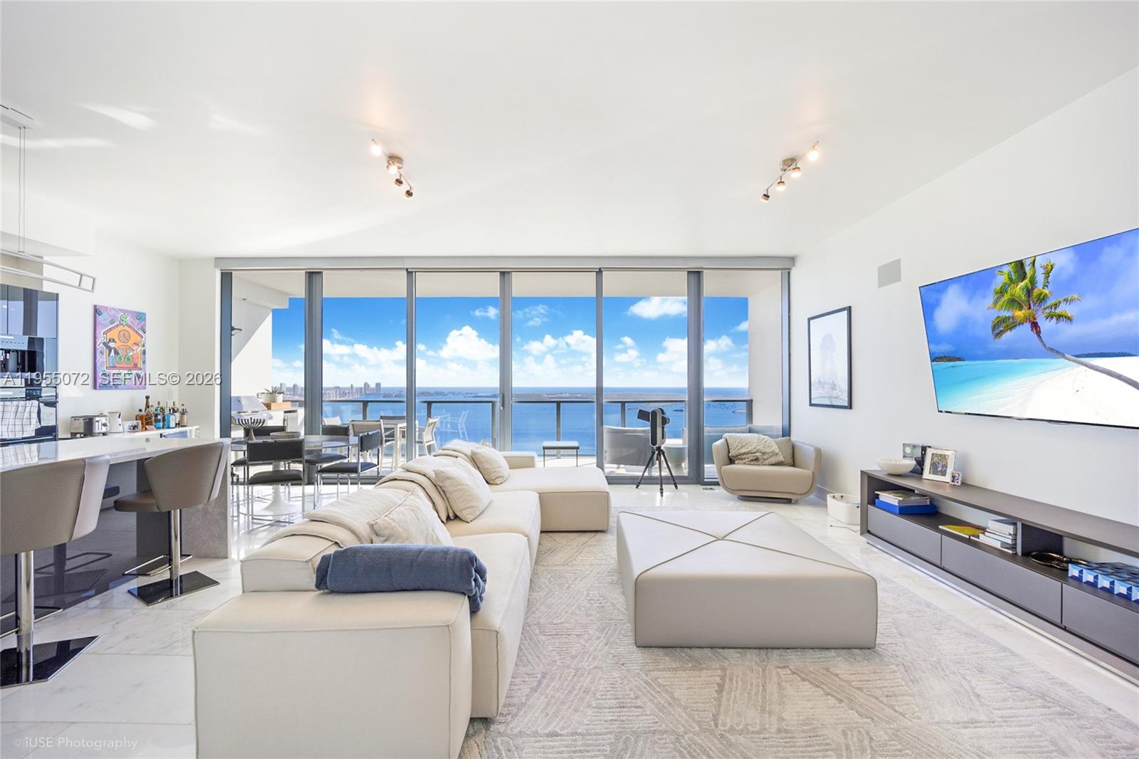 A modern living room features a large sectional sofa, a television, and floor-to-ceiling ocean views — 1451 Brickell Ave # 3902, Miami FL 33131, MIAMI, FL