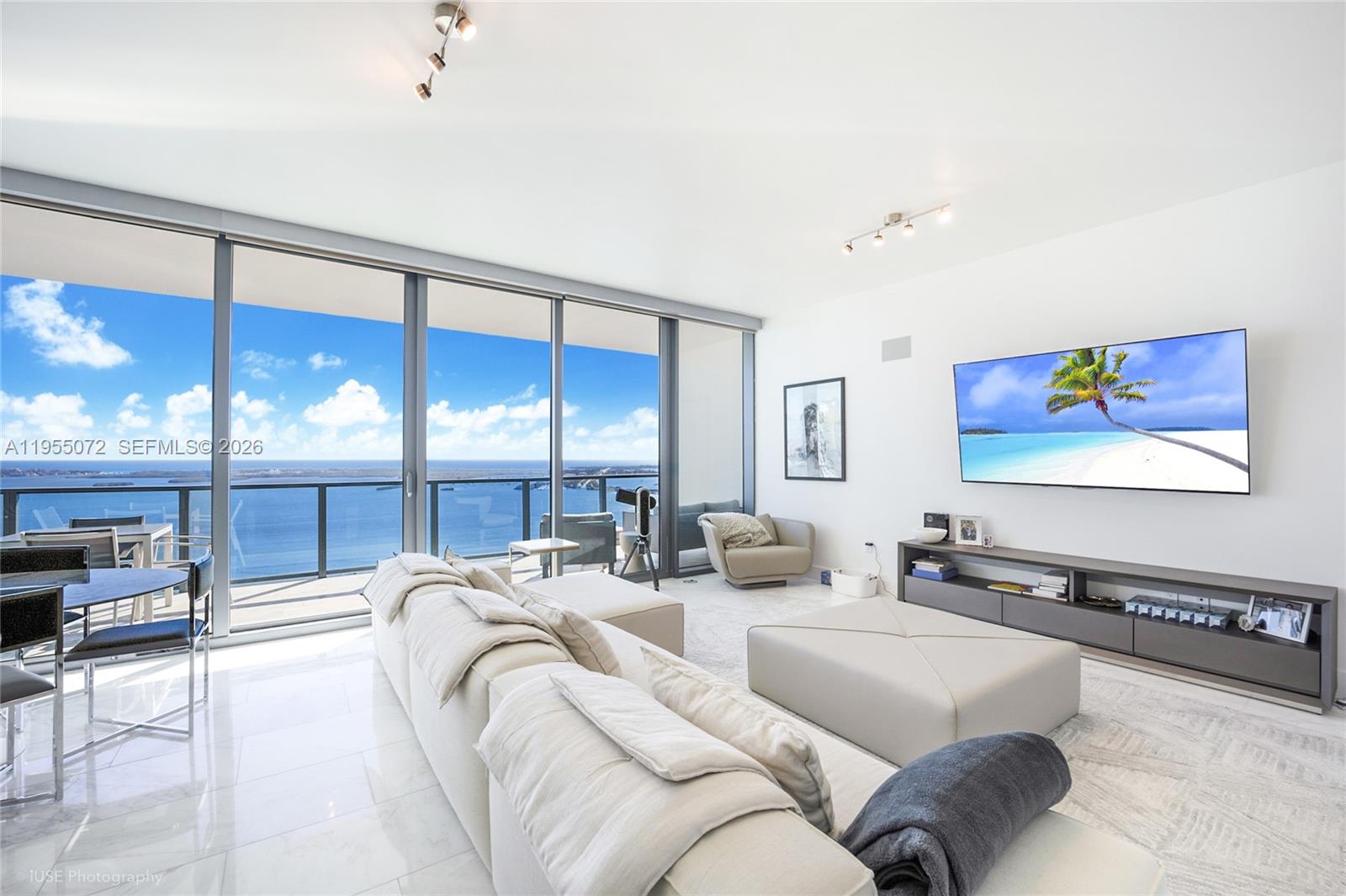 A modern living room features a large sectional sofa, wall-mounted television, and floor-to-ceiling ocean views — 1451 Brickell Ave # 3902, Miami FL 33131, MIAMI, FL