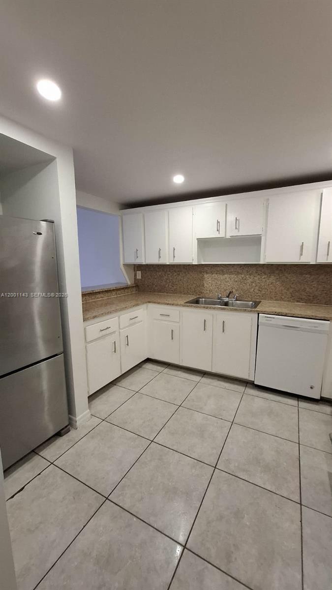 A kitchen features white cabinets, granite countertops, a stainless steel refrigerator, and tiled flooring — 6950 Miami Gardens Dr # 201, Hialeah FL 33015, HIALEAH, FL
