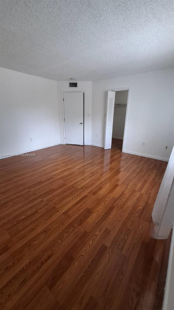 An empty room features white walls, a closet with an open door, and wood flooring — 6950 Miami Gardens Dr # 201, Hialeah FL 33015, HIALEAH, FL