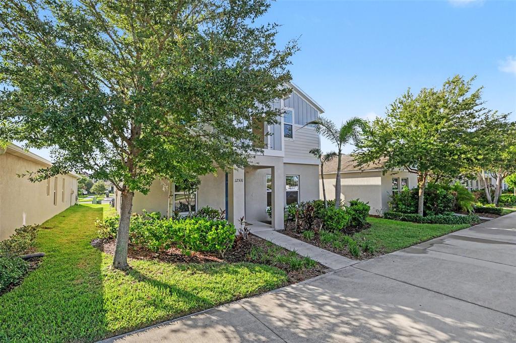 A two-story house with a beige stucco exterior, a small front porch, and landscaping — 12531 TRIPLE CREEK BOULEVARD, RIVERVIEW, FL