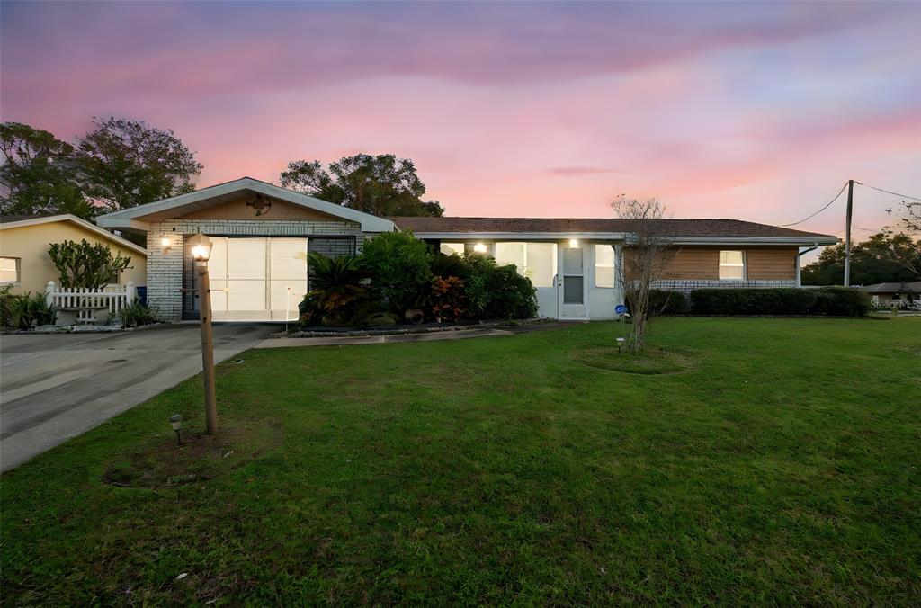 A single-story house with a white brick facade, a driveway, and a large front lawn — 630 GRAND PLAZA DRIVE, ORANGE CITY, FL