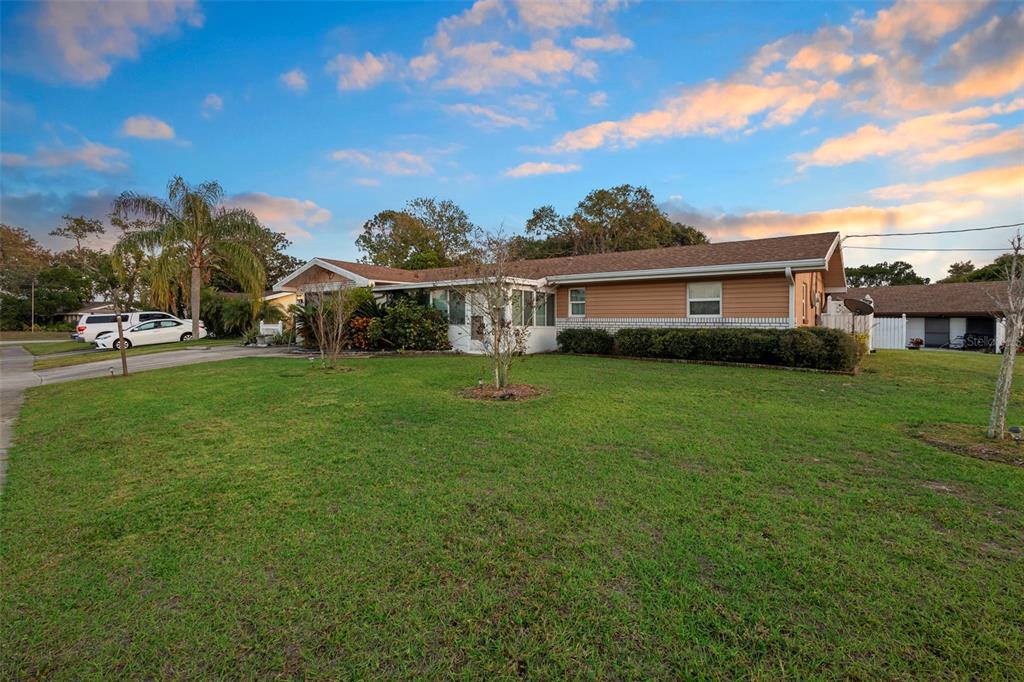 A single-story house with tan siding and a brick base sits on a grassy lot — 630 GRAND PLAZA DRIVE, ORANGE CITY, FL