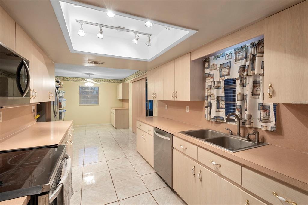 A galley kitchen features light wood cabinets, laminate countertops, tile flooring, and recessed ceiling lighting — 630 GRAND PLAZA DRIVE, ORANGE CITY, FL