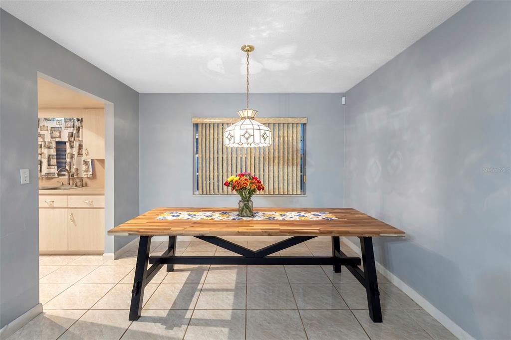 A dining room features a wooden table, a hanging pendant light, and light-colored tile flooring — 630 GRAND PLAZA DRIVE, ORANGE CITY, FL