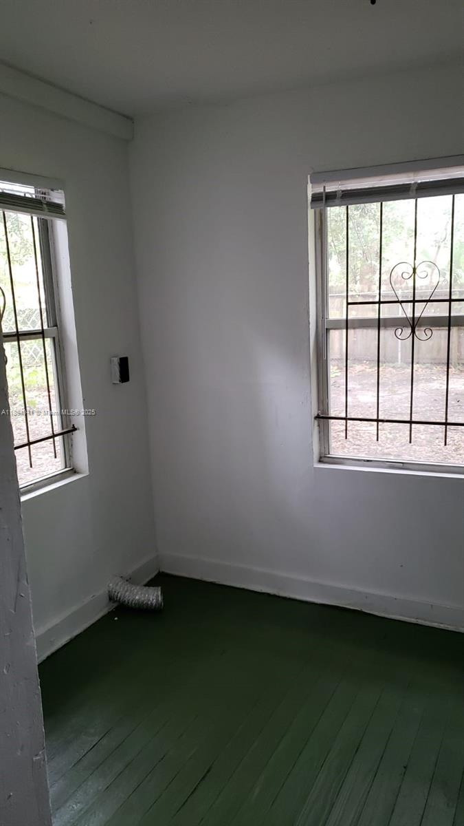 An empty room with white walls, green painted wood floors, and windows with security bars — 1517 Logan # 0, Jacksonville FL 32209, JACKSONVILLE, FL