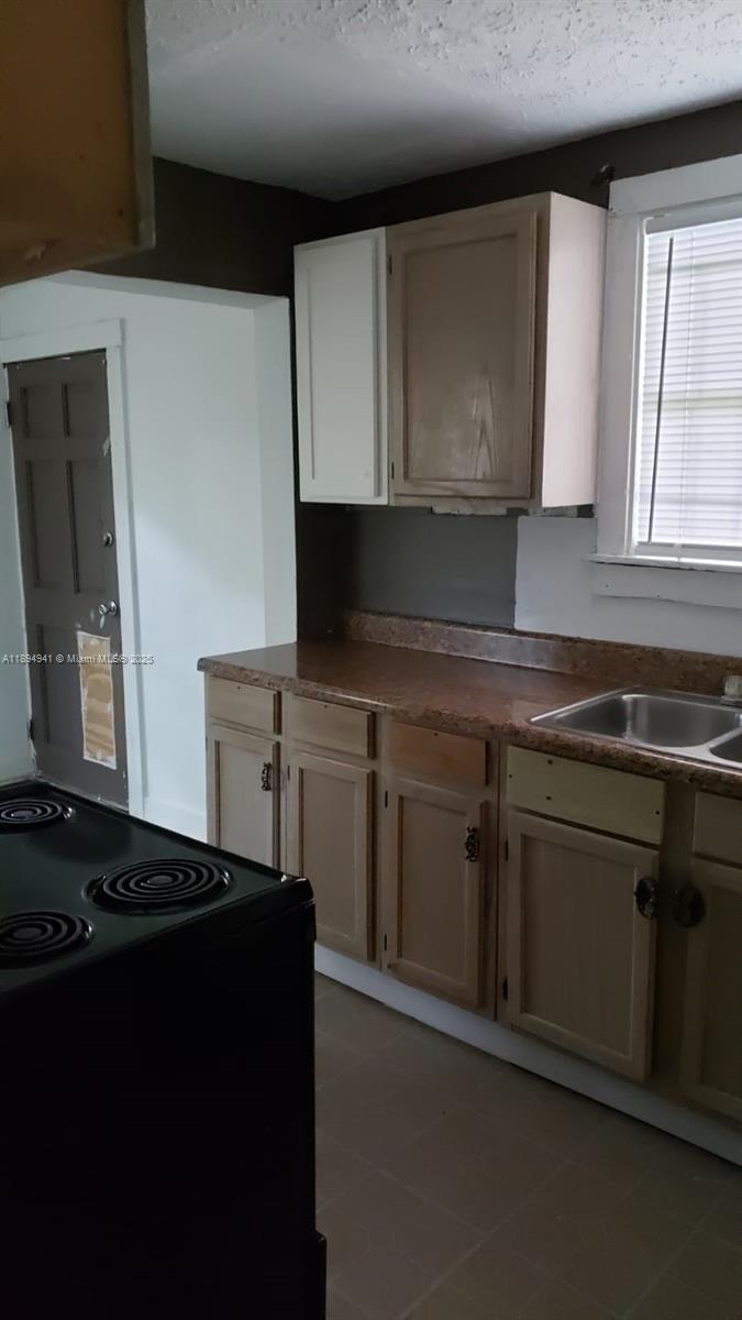 A kitchen features brown cabinets, a granite-look countertop, a stainless steel sink, and a stove — 1517 Logan # 0, Jacksonville FL 32209, JACKSONVILLE, FL