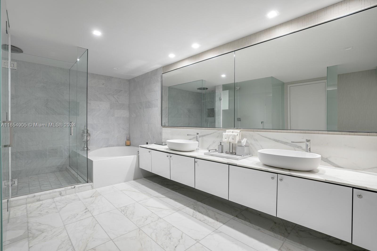 A modern bathroom features a double vanity, a glass-enclosed shower, and a soaking tub — 10203 Collins Ave # 801, Bal Harbour FL 33154, BAL HARBOUR, FL