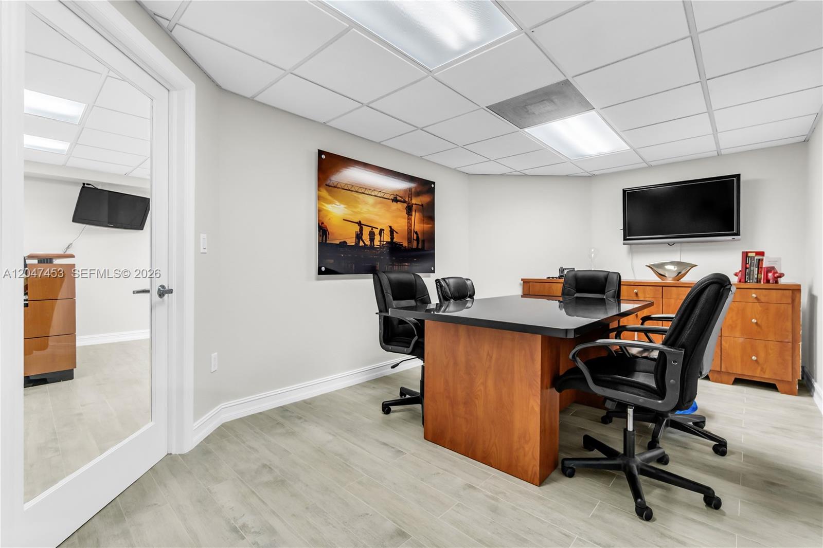 This office features a conference table, black chairs, wood cabinetry, and a construction-themed wall print — 16155 SW 117th Ave # B17, Miami FL 33177, MIAMI, FL