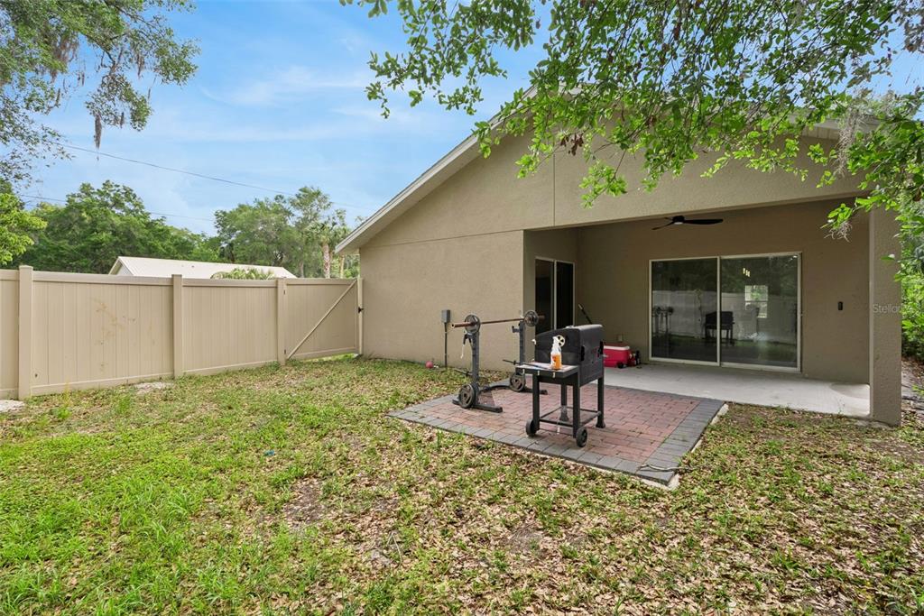 A backyard with a brick patio, a grill, a weight rack, and a vinyl fence — 520 S KENTUCKY AVENUE, DELAND, FL