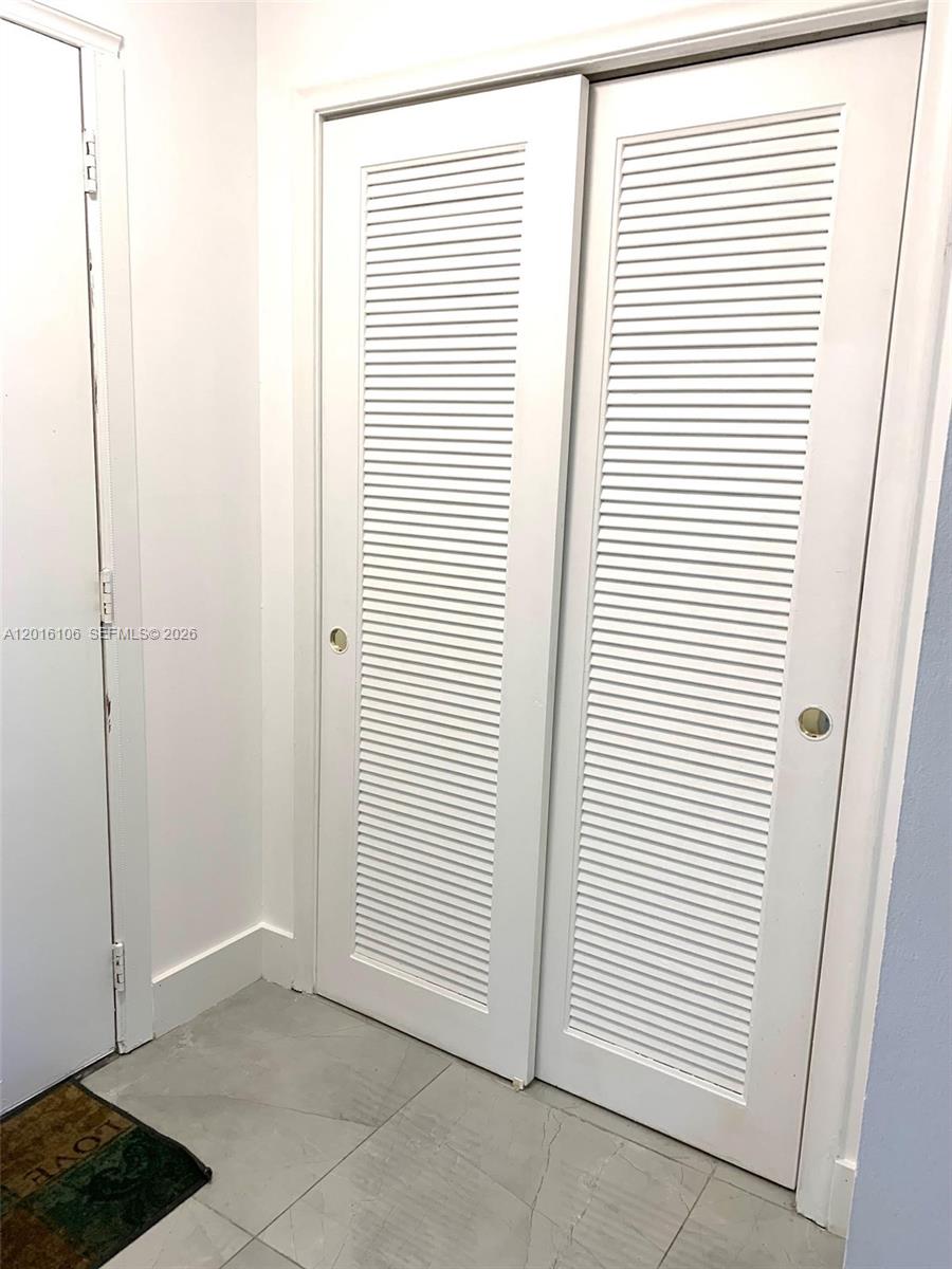 A pair of white louvered sliding closet doors are set against a white wall — 501 NE 14th Ave # 601, Hallandale Beach FL 33009, HALLANDALE BEACH, FL