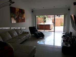 A living room with a white sofa, a black chaise lounge, and a backyard hot tub — 546 NE 199th Ln # 4W, Miami FL 33179, MIAMI, FL