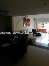 A living room with a sofa, a lounge chair, and a sliding glass door — 546 NE 199th Ln # 4W, Miami FL 33179, MIAMI, FL