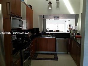 A kitchen with wood cabinets, black countertops, and a stainless steel dishwasher and microwave — 546 NE 199th Ln # 4W, Miami FL 33179, MIAMI, FL