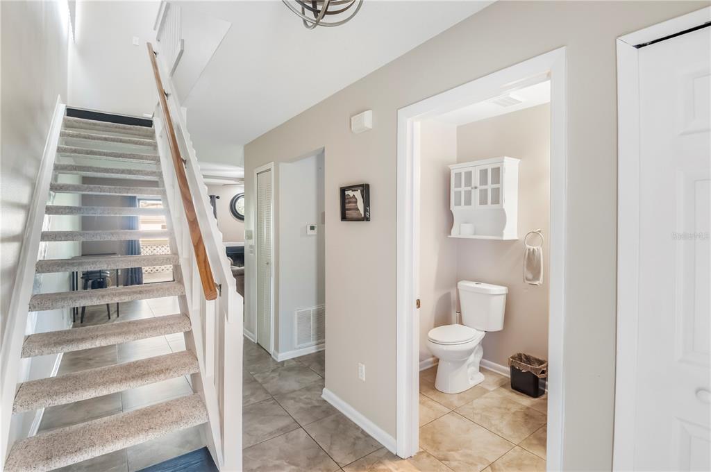 A staircase with carpeted steps leads upward next to a hallway and a small bathroom — 321 ORANGE BLOSSOM DRIVE, WINTER HAVEN, FL