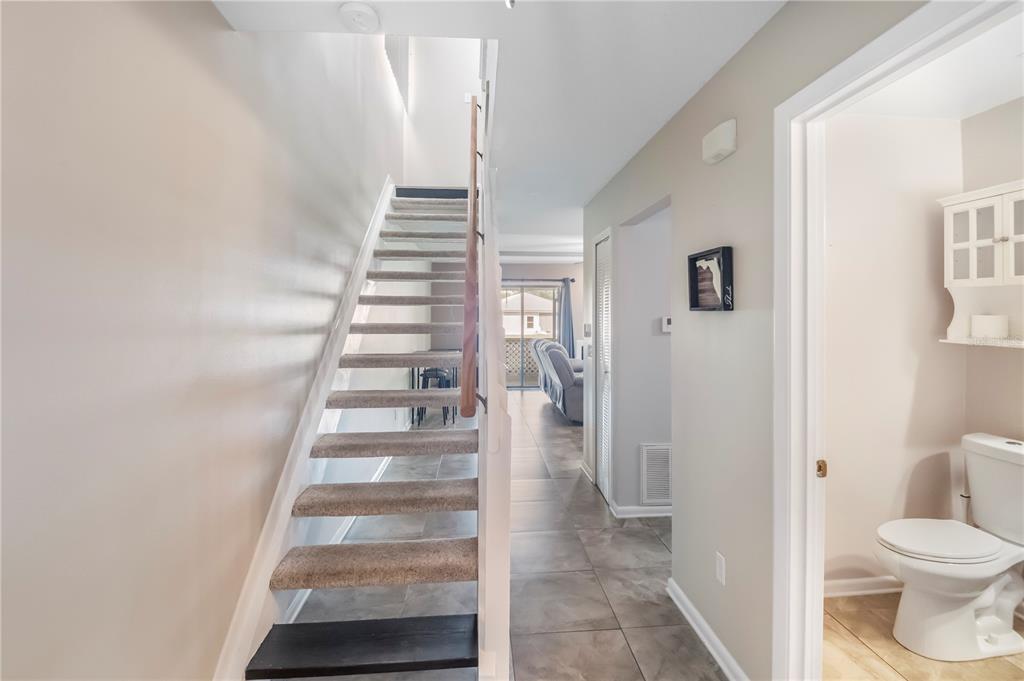 A hallway features a carpeted staircase, tile flooring, and an adjacent half bathroom — 321 ORANGE BLOSSOM DRIVE, WINTER HAVEN, FL