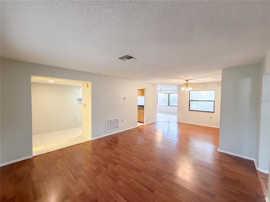 An open-concept living area features hardwood flooring, light gray walls, and a ceiling fan — 3413 SNOWY EGRET COURT, PALM HARBOR, FL