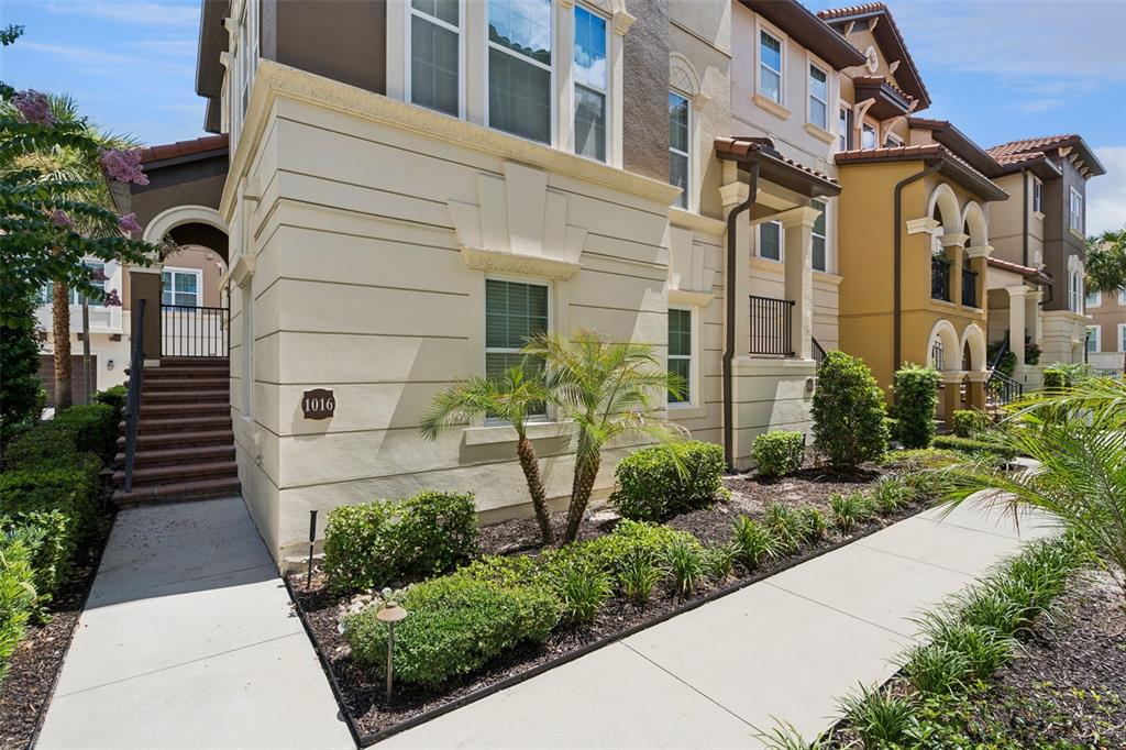 A multi-story tan stucco building features a staircase leading to an arched entryway — 1016 PARMA CIRCLE, LAKE MARY, FL