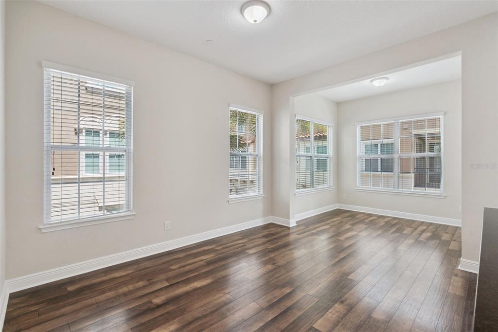 An empty room with wood-look flooring, white walls, and four windows with white blinds — 1016 PARMA CIRCLE, LAKE MARY, FL