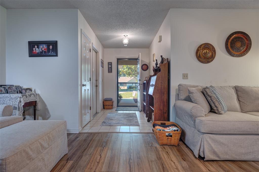 An entryway with tile flooring leads to an open front door, flanked by a living area — 1055 W VILLAGE GREEN RD, DELAND, FL